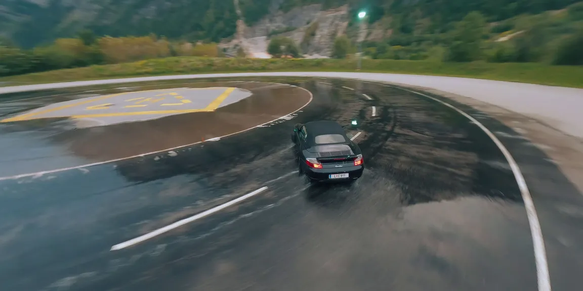 Porsche Fahrzeug fährt auf nasser Kurve