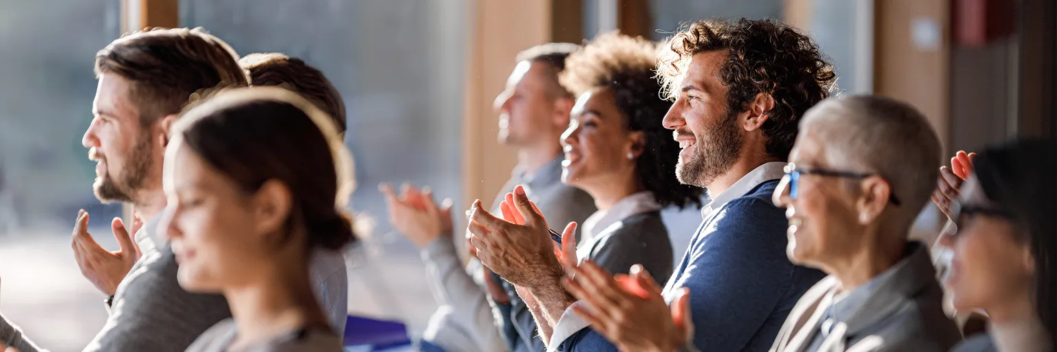Blick in eine Versammlung mit applaudierenden Personen.