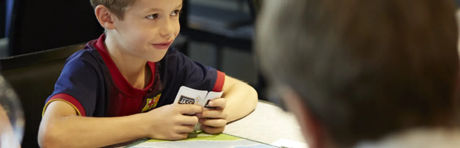 Junge mit Jasskarte schaut gewievt