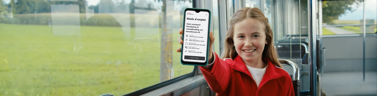 Une jeune fille montre un écran mobile avec des héros locaux