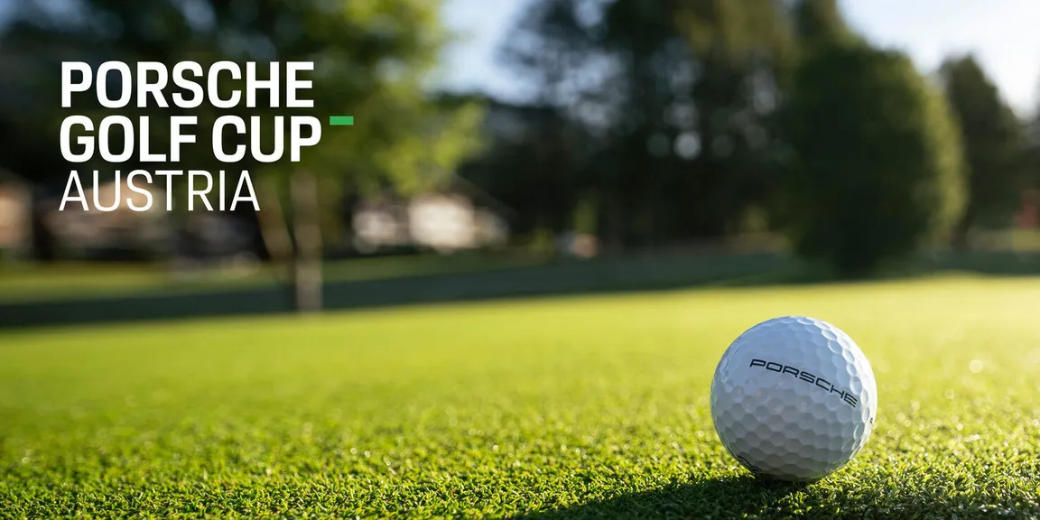 Golfball mit Porsche Logo liegt auf einem Green.